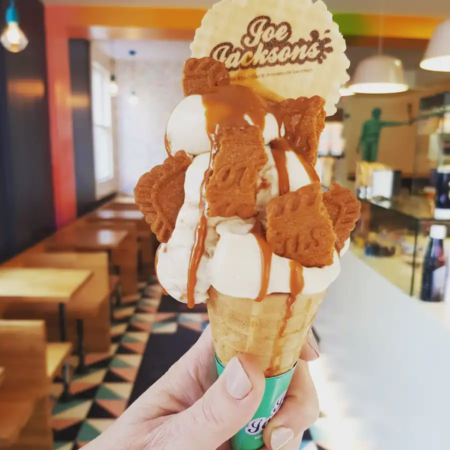 Biscoff ice cream in a cone with topping of biscuit and biscoff sauce