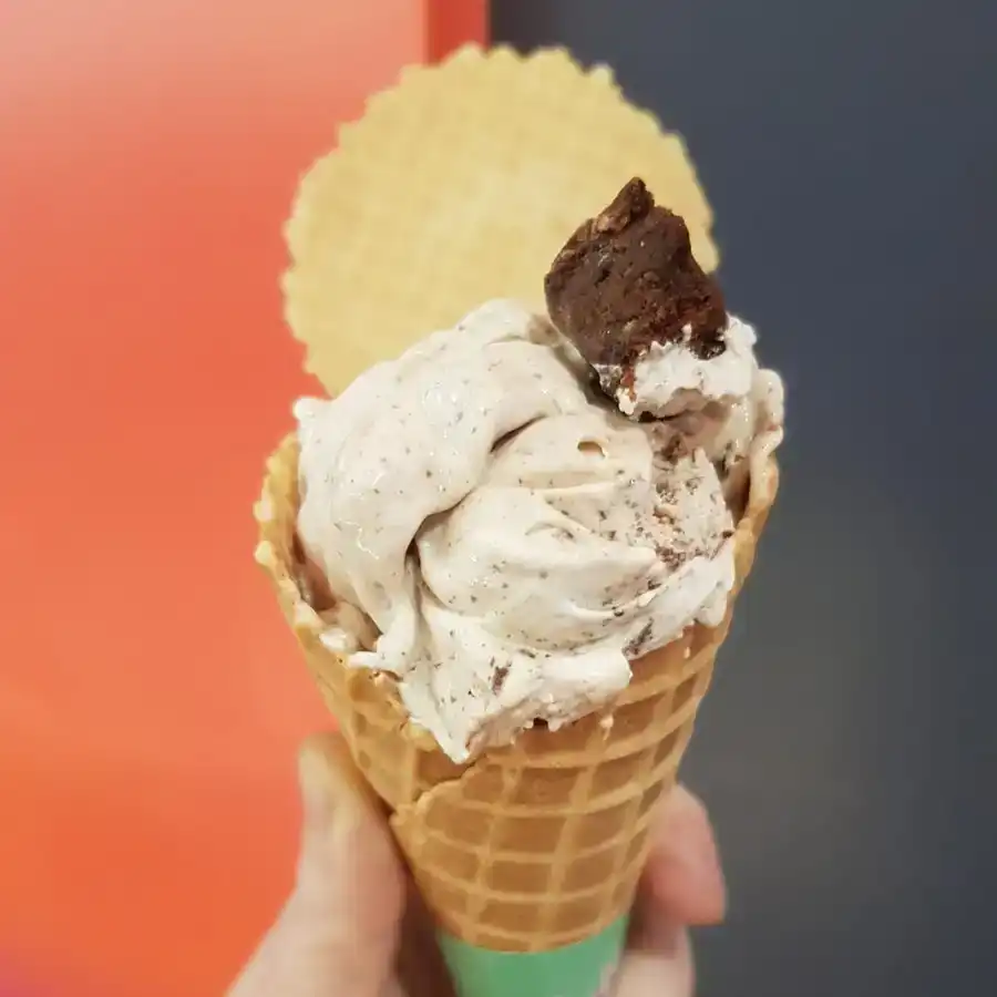 Chocolate brownie ice cream in a cone with small chunk of brownie and a wafer with joe jackson name on it