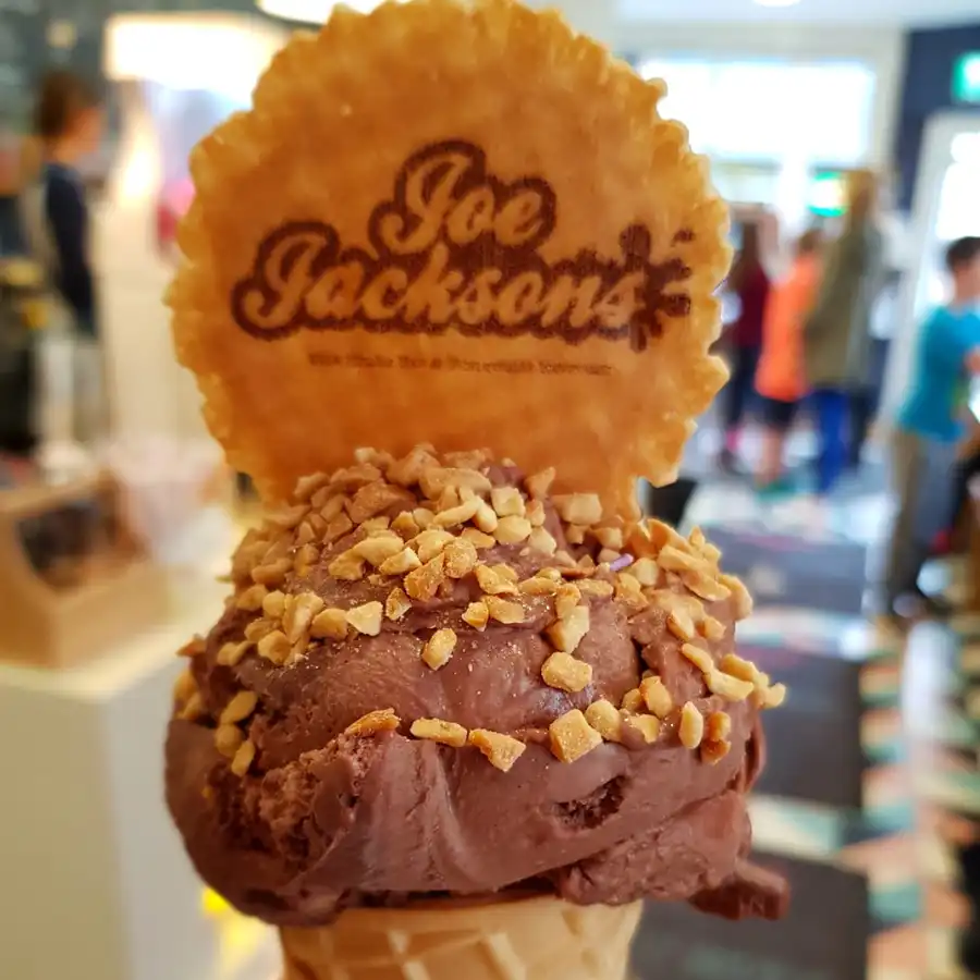 Double chocolate scoop in a cone with peanut topped and a wafer with joe jackson name on it