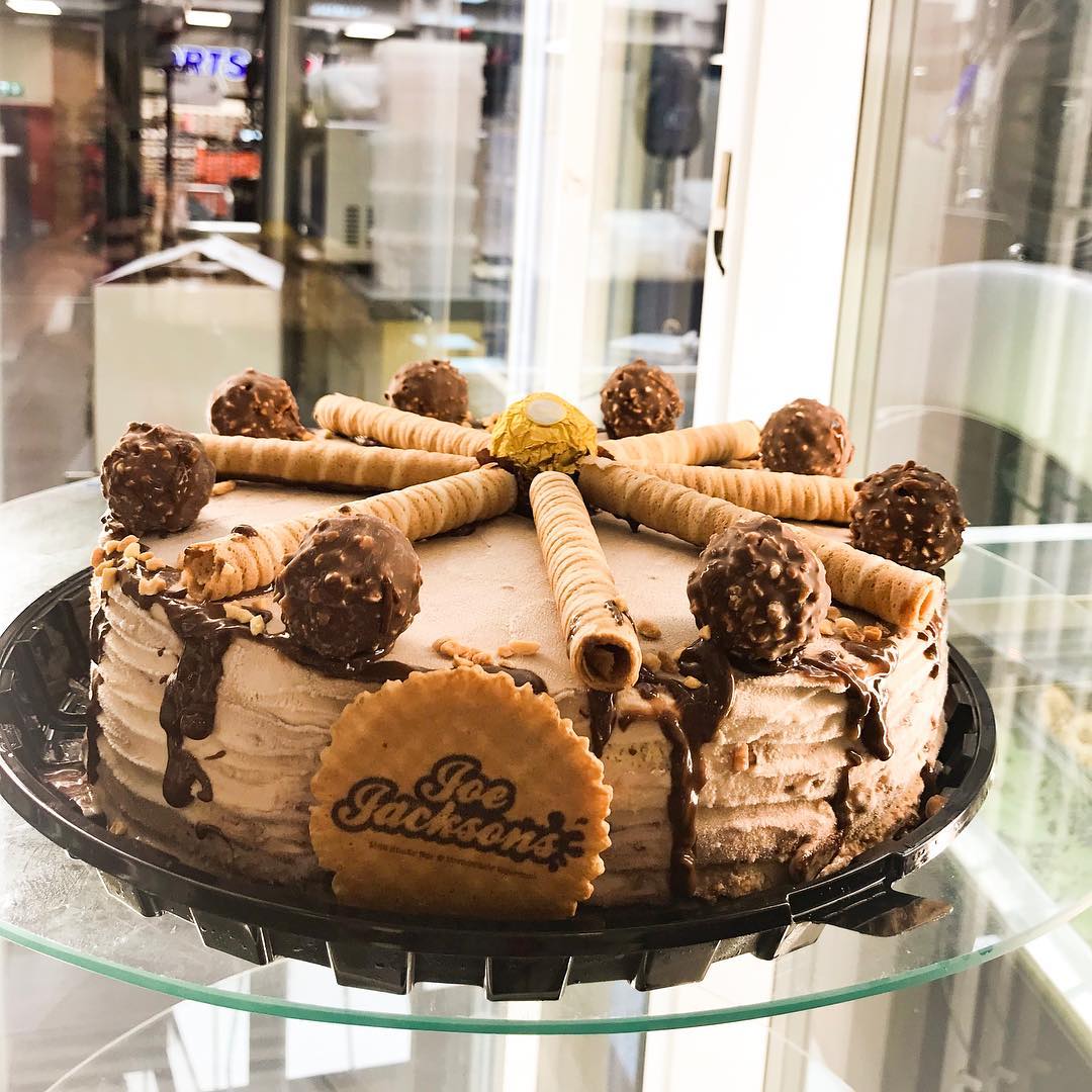 Ferrero rocher ice cream cake topped with ferrero sweets, chopped hazelnuts, sweet curls and a wafer with joe jackson name on it