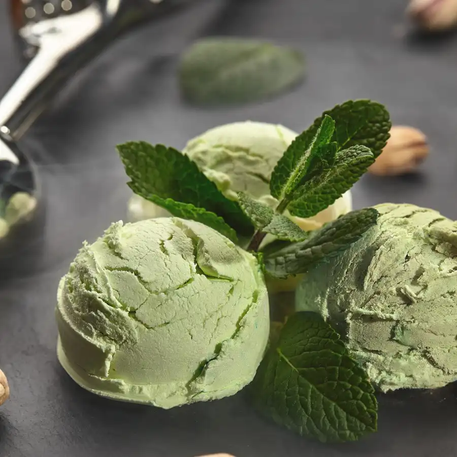 Three pistachio ice cream scoop with mint leaves