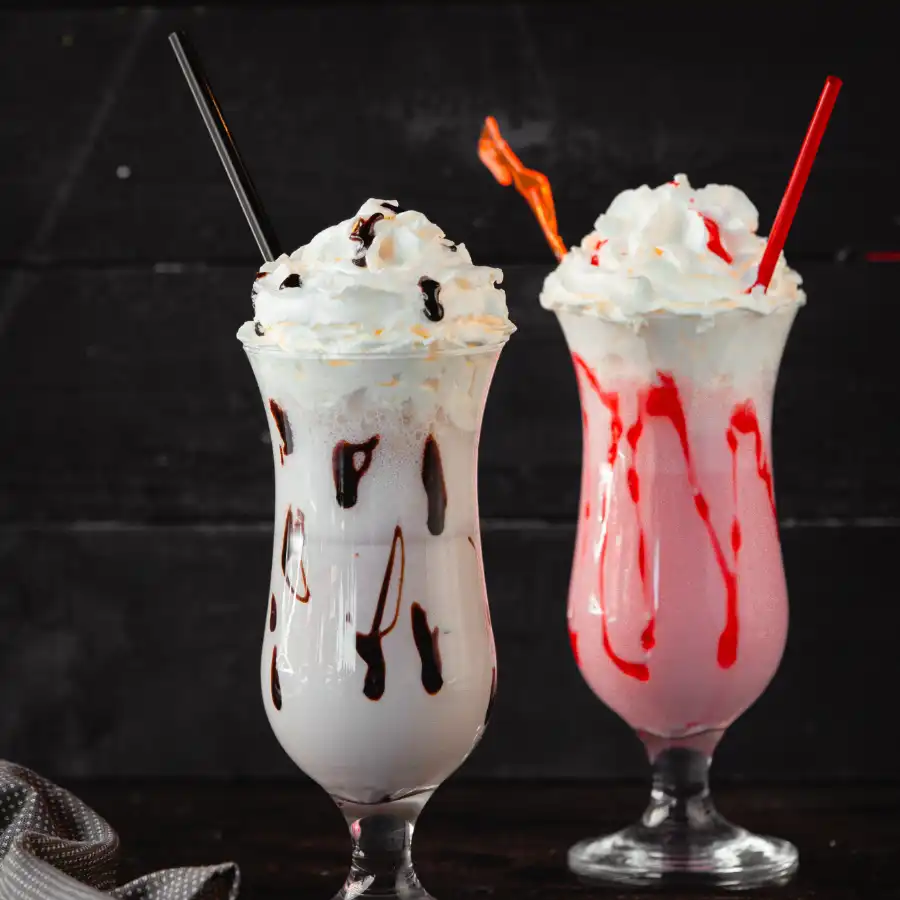 Strawberry and vanilla milkshake on table with straws