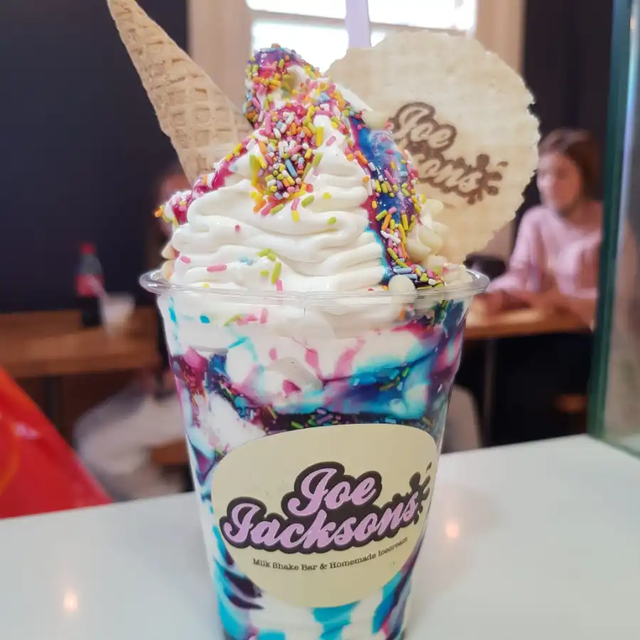 Unicorn sundae topped with colourful sprinkles, cone and a wafer with joe jackson name on it